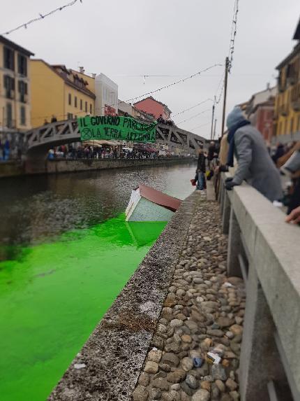 Extinction Rebellion - Extinction Rebellion il 09/12/2023: A Milano il Naviglio Grande si è tinto di verde mentre una casa di cartapesta 'affondava' tra le acque e dal ponte Alda Merini e uno striscione urlava 'il governo parla, la Terra affonda'.