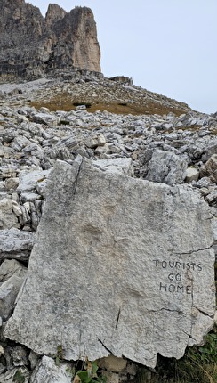 Tre Cime di Lavaredo, Dolomites - Tourists go home, the vandalized boulder with dinosaur footprints at Tre Cime di Lavaredo, Dolomites