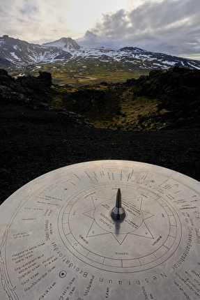 Islanda in sci - Islanda: dalla cima di un piccolo cono vulcanico, una rosa dei venti indica la cima, nascosta fra le nubi dello Snæfellsjökull, il vulcano dove Jules Verne fa iniziare il suo Viaggio al Centro della Terra.