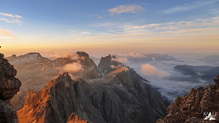 Ruggero Alberti fotografo, Dolomiti - Le Dolomiti di Ruggero Alberti: foto scattata all'alba poco sotto la  vetta del Cimon della Pala. Sullo sfondo l'altopiano delle Pale di San Martino illuminato dai primi raggi di sole e in ombra la valle del Primiero sotto le nuvole.