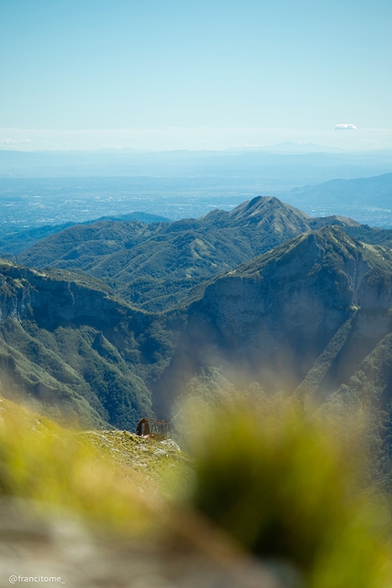 Alpi Apuane traversata alpinistica, Francesco Bruschi, Francesco Tomé  - Alpi Apuane da Nord a Sud: visuale dalla vetta del Monte Corchia. Si notano i resti del bivacco Lusa-Lanzoni, distrutto ormai molti anni addietro in seguito agli scontri accesi tra gli speologi e i cavatori del vicino paese di Levigliani. Il paesaggio spazia poi sulla vetta del monte Croce e più in lontananza le cime del monte Piglione Nord e Sud e le città della Toscana.